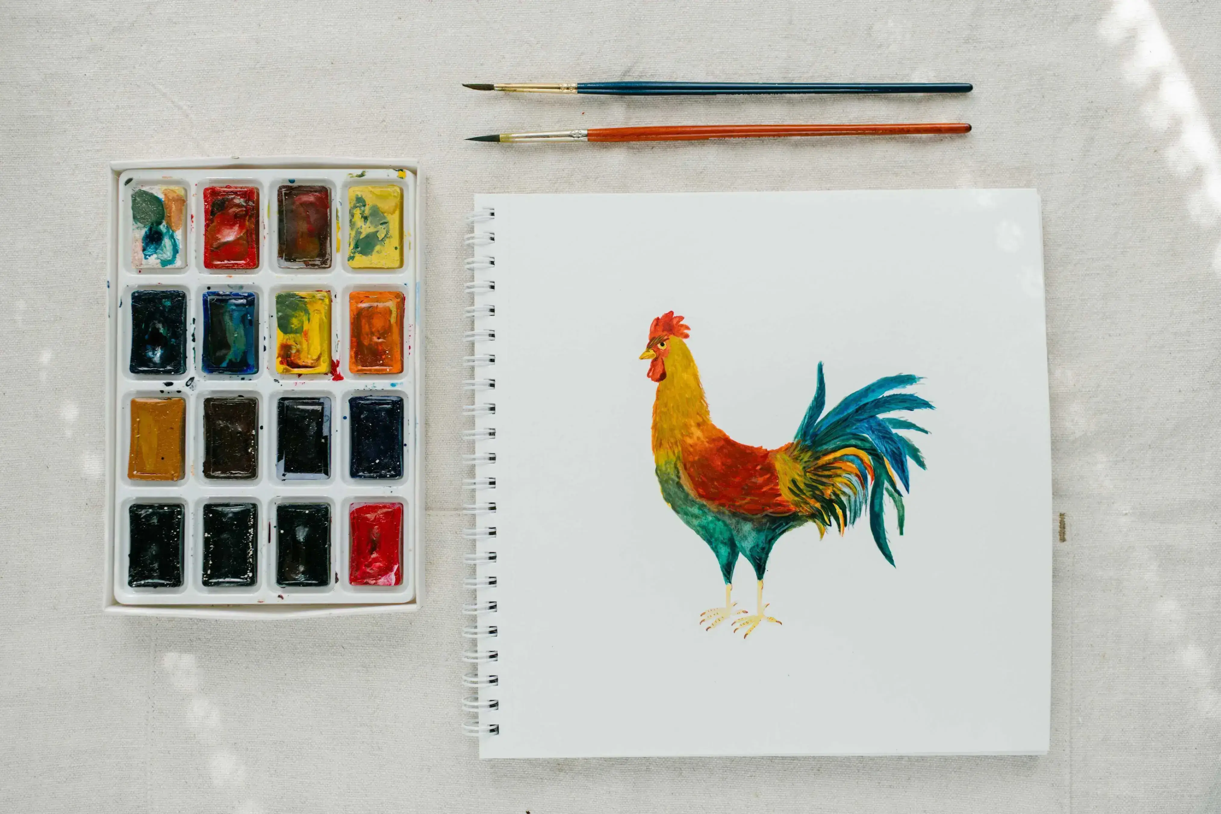 A colourful watercolour painting of a rooster on a canvas.